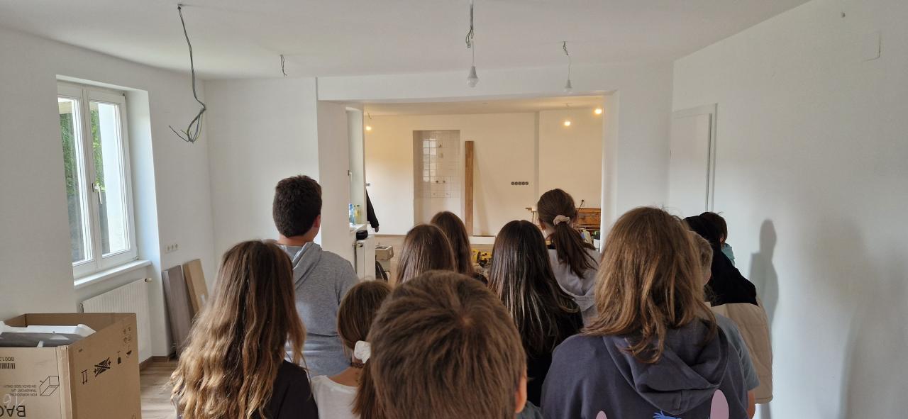 Eine Klasse der Mittelschule besucht die Bibliothek im Rohzustand und entscheidet, wo das Jugendregal stehen wird. Danach werden Bücher beim Bookcasting im Gemeindesaal bewertet.