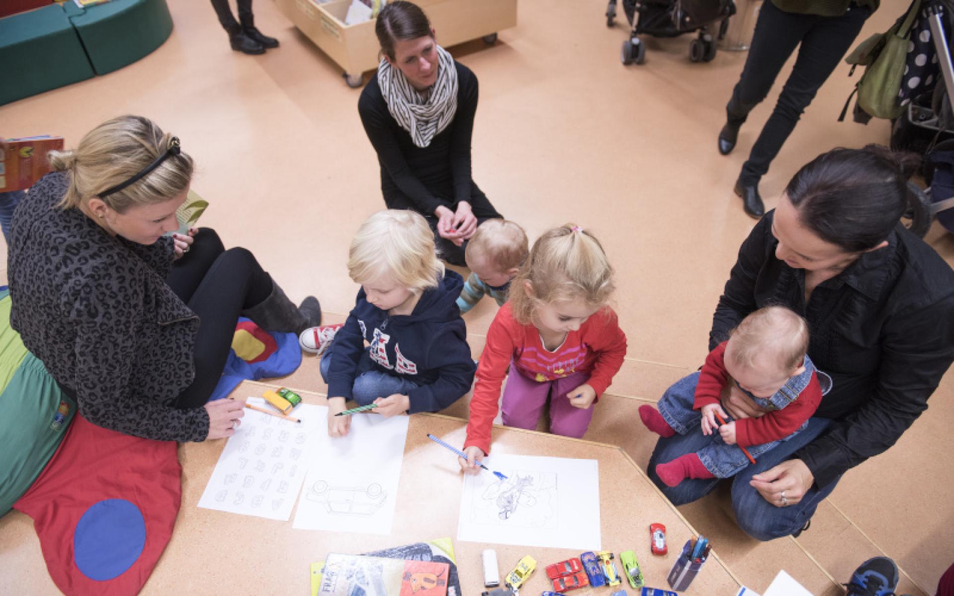 Symbolbild: Eltern mit Kinder in der Bibliothek